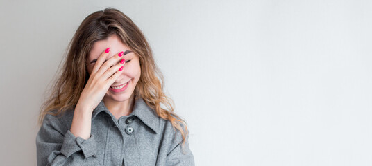 So dumb but so sweet. Studio shot of attractive stylish woman making facepalm, holding hand on eyes and smiling, coming to terms with stupid sense of humour of boyfriend