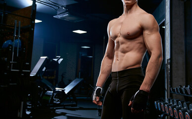 Fototapeta na wymiar Incognito shirtless sportsman posing in gym.