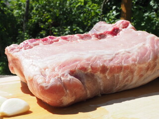 pork loin on the bone with garlic on a wooden Board. cooking in nature. against the background of fire