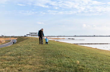 Man with toddler walking on dyke