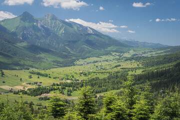 Fototapeta na wymiar Beautiful elevated view of mountains in Slovakia. Bachledova dolina, Zdiar village and Belianske Tatry mountains seen from an elevated viewpoint on a hiking trail on summer day