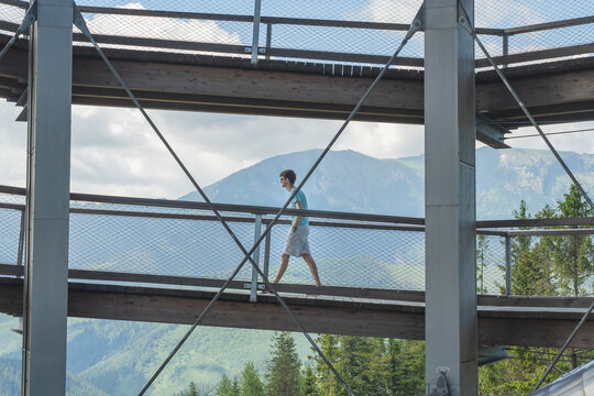 Young adult caucasian man walking up on an elevated walkway with nature and mountain in background