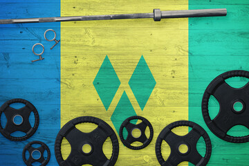 Saint Vincent And The Grenadines gym concept. Top view of heavy weight plates with iron bar on...