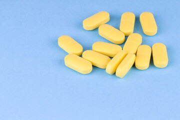 The yellow pills scattered onto the blue surface. Medicine.