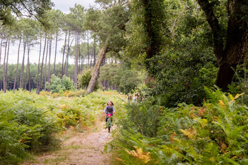 Obraz premium cute little girl riding a bicycle in the forest with her mom