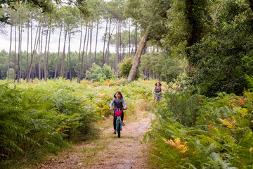 Obraz premium cute little girl riding a bicycle in the forest with her mom