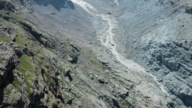 Aerial shot revealing high mountain range behind glacier ending in Alp