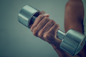 Closeup and selective focus on the hand of a black woman holding a dumbbell.