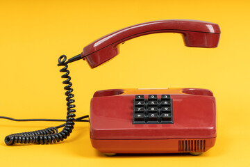 Old red telephone on yellow background. Vintage red phone with taken off receiver