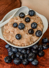 Oatmeal with blueberries. Healthy breakfast. Wooden background. Top view. Selective soft focus. Shallow depth of field.