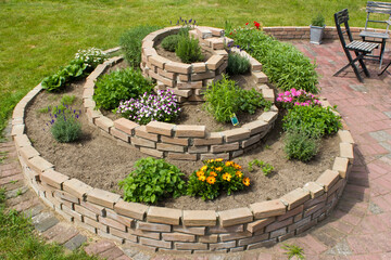 herb spiral in the garden with herbs and flowers