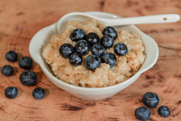 Oatmeal with blueberries. Healthy breakfast. Wooden background. Top view. Selective soft focus. Shallow depth of field.
