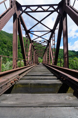Fototapeta na wymiar Railway bridge over river in moutains. Old rusty railway bridge.