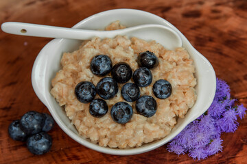 Oatmeal with blueberries. Healthy breakfast. Wooden background. Top view. Selective soft focus. Shallow depth of field.