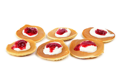 Pancakes with sour cream and raspberry jam on white background
