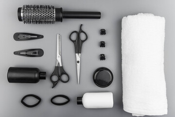 Professional hair dresser tools with copy space. Hair stylist equipment set on gray background. Scissors, brush, hairbrush, balm flat lay top view.