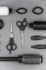 Professional hair dresser tools with copy space. Hair stylist equipment set on gray background. Scissors, brush, hairbrush, balm flat lay top view.