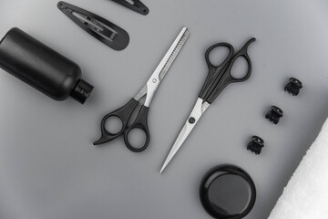 Professional hair dresser tools with copy space. Hair stylist equipment set on gray background. Scissors, brush, hairbrush, balm flat lay top view.