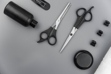 Professional hair dresser tools with copy space. Hair stylist equipment set on gray background. Scissors, brush, hairbrush, balm flat lay top view.