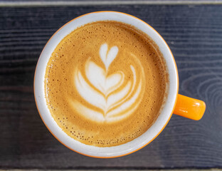 Italian cappuccino coffee orange and white cup on dark wood table surface