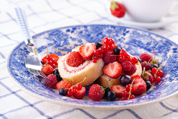 dessert with fresh berries in a blue vintage plate. Sweet roll.