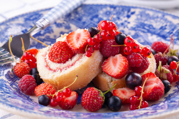 dessert with fresh berries in a blue vintage plate. Sweet roll.