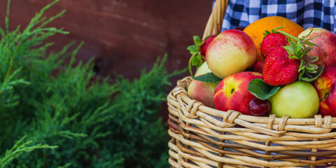 fruit basket in the hands of a girl on a wooden background