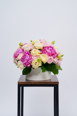 Beautiful flowers bouquet on the wooden chair. Bouquet made of peonies and different roses. Wedding flowers. Valentine's or Women's Day. White background. Vertical photo with free space for text.