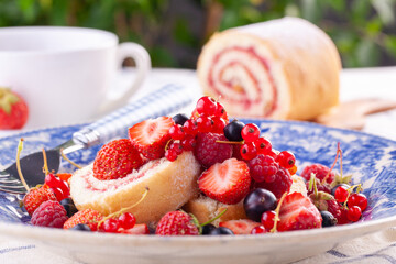 dessert with fresh berries in a blue vintage plate. Sweet roll.