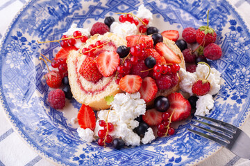 dessert with fresh berries in a blue vintage plate. Sweet roll.