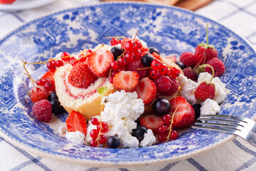 dessert with fresh berries in a blue vintage plate. Sweet roll.