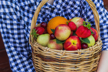fruit basket in the hands of a girl on a wooden background