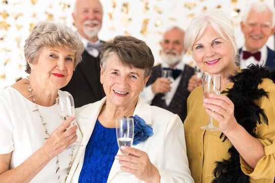 Three Elegant Older Friends Make A Toast With Champagne During The Birthday Party