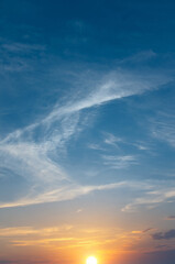 Soft sunset against the backdrop of blue sky and textured clouds.
