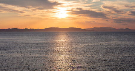 Fototapeta premium Sunrise, sunset clouds. Twilight, dusk cloudy sky over sea water, mountain silhouette