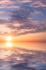 Sunset over the sea with bright sunrays and textured clouds.
