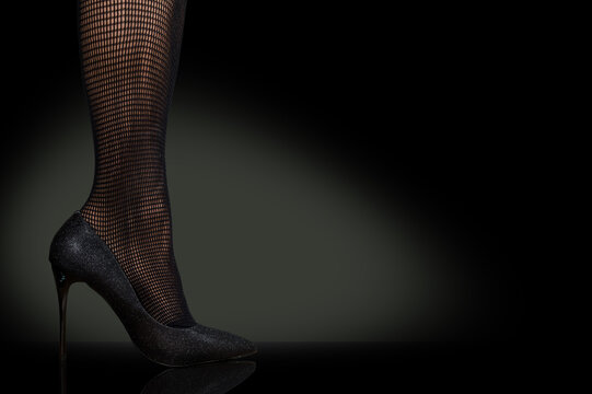 Close up high heeled women with fishnet tight on black background.