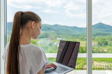 Cute smiling woman using laptop at home. Student girl working on computer