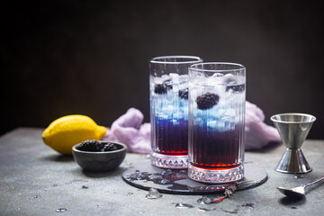 Refreshing Blackberry Lemonade with ice in crystal glasses on gray background