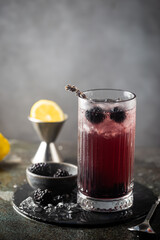 Refreshing Blackberry Lemonade with ice in crystal glasses on gray background