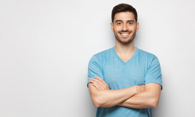 Banner of young handsome man wearing blue t-shirt, standing with crossed arms, isolated on studio...