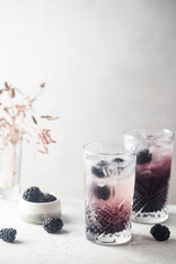 Refreshing Blackberry Lemonade with ice in crystal glasses on white background