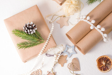 Fototapeta na wymiar christmas gift box packed in kraft paper and decorated with a fresh spruce branch and a pine cone, natural materials for decorating gifts on a white background, eco friendly christmas concept