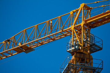 Fototapeta na wymiar Yellow tower crane working on building against blue sky, selective focuse