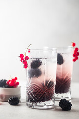 Refreshing Blackberry Lemonade with ice in crystal glasses on white background