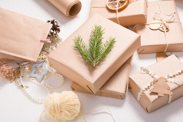 several Christmas gift boxes in eco friendly style on a white background, decorating gifts with wooden figures and natural materials, a box decorated with a spruce branch