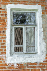 dilapidated red brick window of an old village house. Not neatly painted