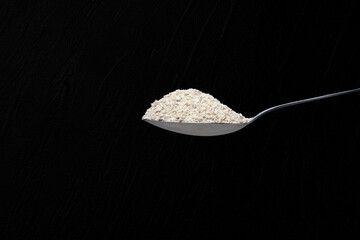 Isolated spoon full of oats flower in a black background