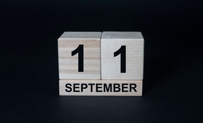 Wood blocks in box with date, day and month 11 September. Wooden blocks calendar on black background
