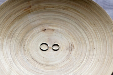 Gold wedding rings on rustic wooden plate. Selective focus.